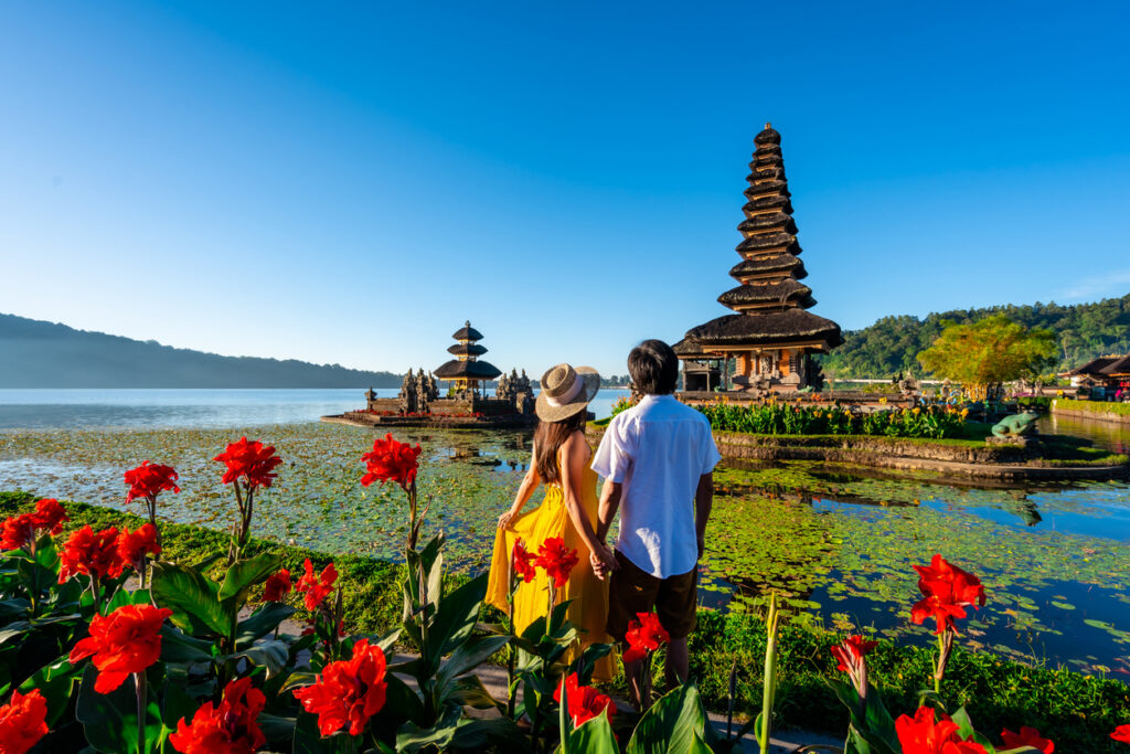 Young couple tourist relaxing and enjoying their honeymoon in May and the beautiful view at Ulun Danu Beratan temple in Bali, Indonesia
