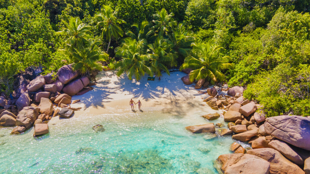 Praslin Seychelles tropical island with withe beaches and palm trees, couple of men and women mid age on vacation at Seychelles visiting the tropical beach Anse Lazio Praslin Seychelles. drone view